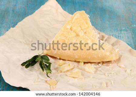 Piece of Parmesan cheese on paper on wooden table close-up