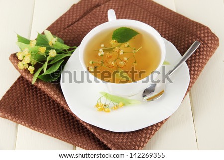 Cup of tea with linden on napkin on  wooden table