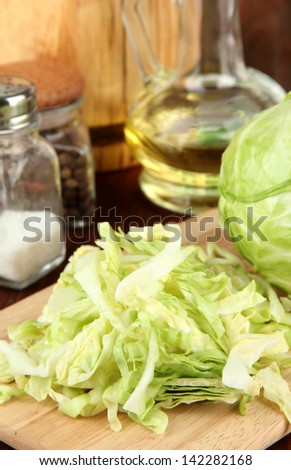 Green cabbage, oil, spices on cutting board, on wooden background