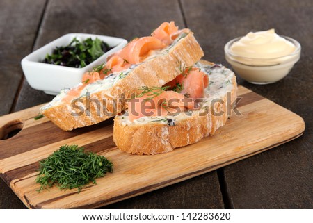 Fish sandwiches on cutting board on wooden table