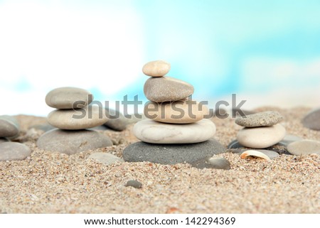 Towers of sea stones on sand on bright background