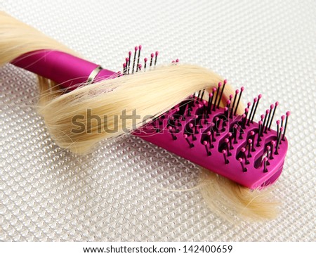 Comb brush with hair, on grey background