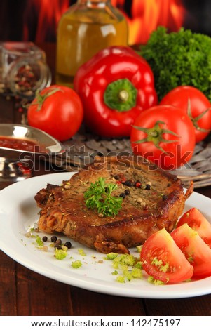 Piece of fried meat on plate on wooden table on fire background
