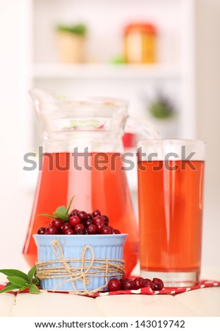 Pitcher and glass of cranberry juice with red cranberries on table