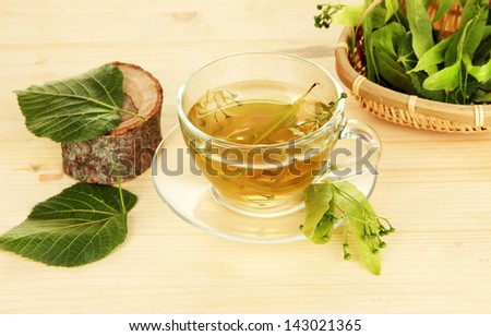 Glass cup of tea with linden on wooden table close-up