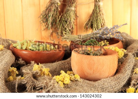 Medicinal Herbs in wooden bowls on bagging on table on wooden background
