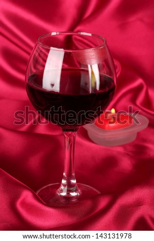 Glass of wine with lipstick imprint on red fabric background