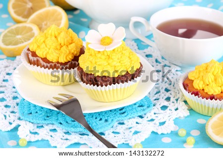Beautiful lemon cupcakes and flavored tea on dining table close-up