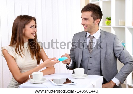 Business partners changing business cards in cafe