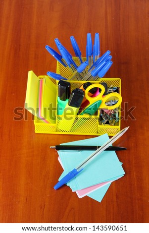 Office equipment in yellow stationary holder on wooden table
