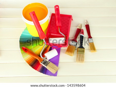 Set for painting: paint pot, brushes, paint-roller on white wooden table