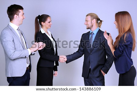 Business colleagues introducing with handshake, on grey background