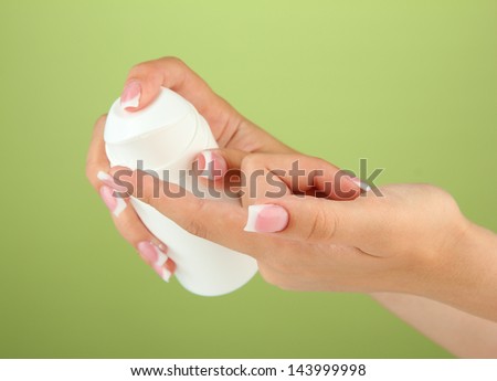 Woman applying cream on hands on color background