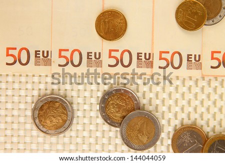 Euro banknotes and euro cents on beige background