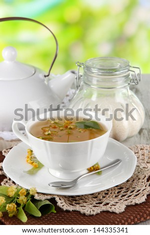 Cup of tea with linden on napkins on    wooden table on nature background
