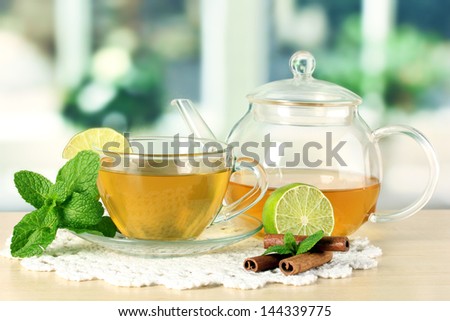 Cup of tea with mint,lime and cinnamon on table in room