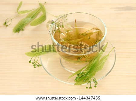Glass cup of tea with linden on wooden table close-up