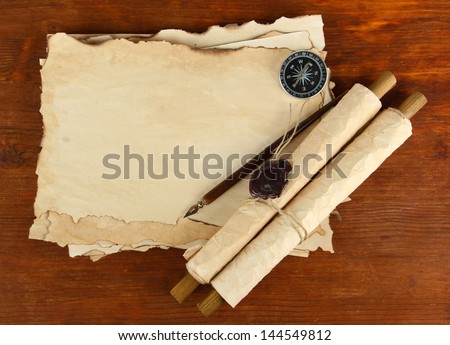 Old paper, scrolls and compass on wooden background