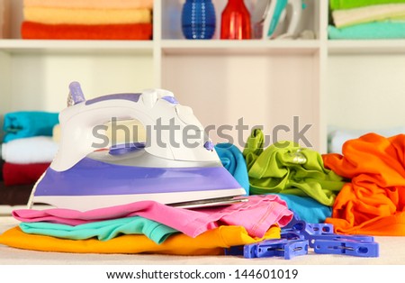 Clothes and iron on table on shelves background