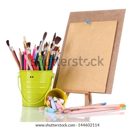 Small easel with sheet of paper with art supplies isolated on white