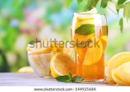 Iced tea with lemon and mint on wooden table, outdoors