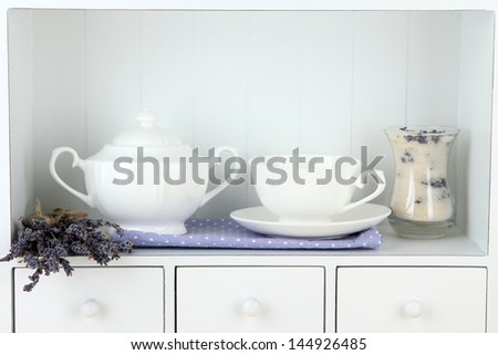 Still life with glass of lavender sugar, cup and fresh lavender flowers on shelves