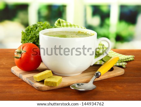 Cup of soup with bouillon cubes on wooden table