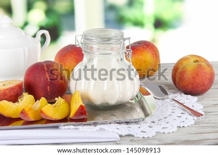 Peaches with sugar on metal tray on napkin on table on window background