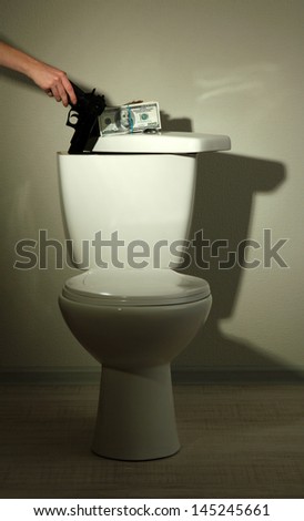 Hand hides gun and money in toilet tank in a bathroom