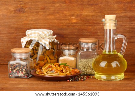 Composition of delicious marinated mushrooms, oil and spices on wooden table on wooden background