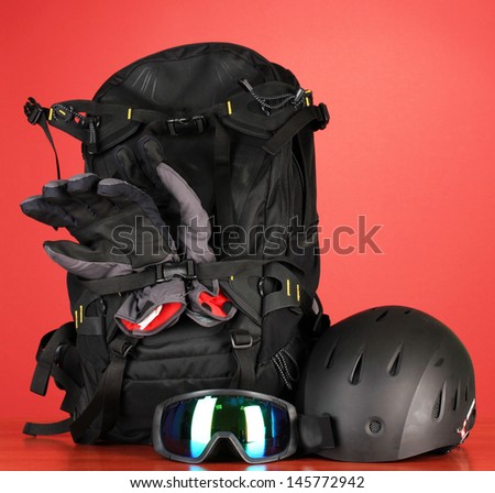 Winter sport glasses, helmet and gloves, backpack, on red background