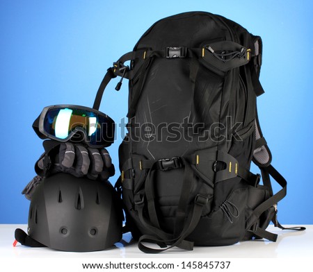 Winter sport glasses, helmet and gloves, backpack, on blue background