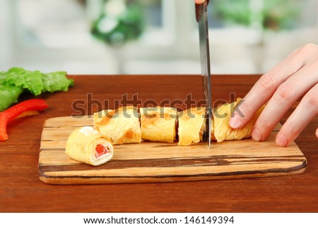 Process of preparing egg rolls, on bright background: cutting egg roll