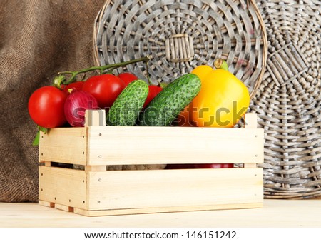 Fresh vegetables in wooden box on burlap and wicker background