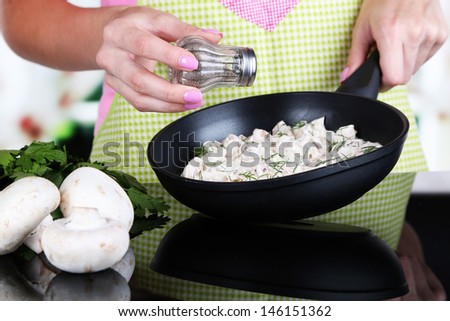 Hands cooking mushroom sauce in pan in kitchen