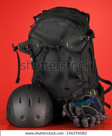 Winter sport glasses, helmet and gloves, backpack, on red background