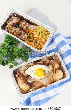 Food in boxes of foil on napkin on wooden board isolated in white