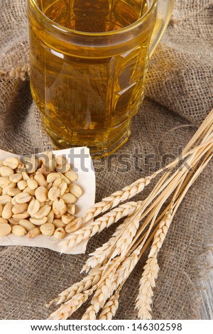 Beer in glass and nuts on bagging on wooden table
