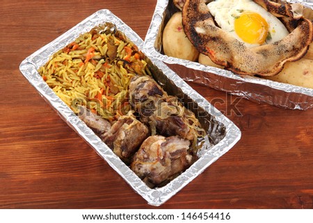 Food in boxes of foil on wooden background