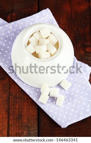 Refined sugar in white sugar bowl on wooden background
