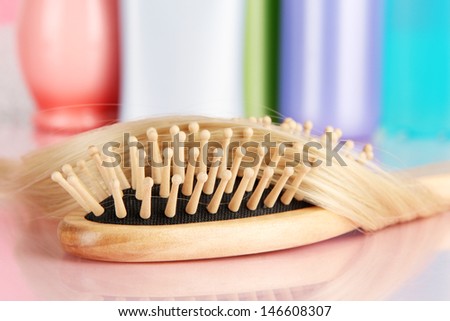 comb brush with hair and cosmetic bottles in bathroom