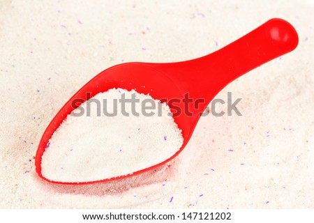 Washing powder in measuring cup on powder background