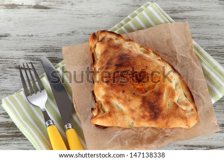 Pizza calzone on tracing paper  on napkin on wooden table