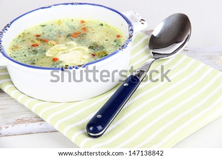 Soup in plate on napkin on wooden board isolated on white