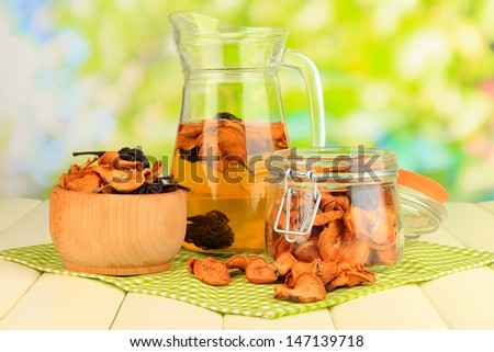 Assorted dried fruits in bowl and compote of dried fruits on wooden table on natural background