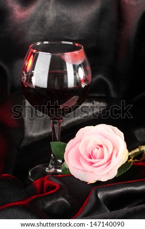 Glass of wine with lipstick imprint on black satin background
