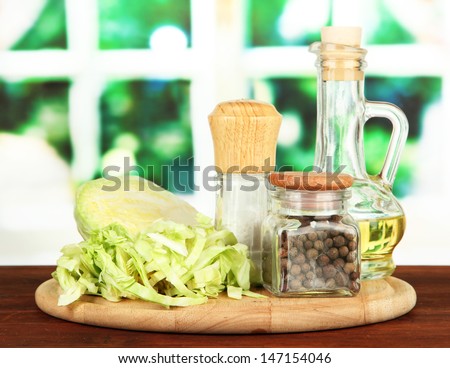 Green cabbage, oil, spices on cutting board, on bright background