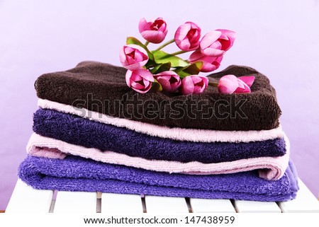Towels and flowers on wooden chair on purple background