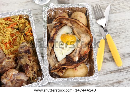 Food in boxes of foil on wooden table