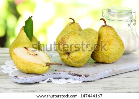 Pears on board on napkin on wooden table on nature background